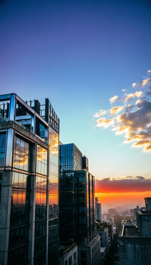 高品质写实风格，柔和的自然光，温暖的日落灯光，细腻的光影效果，城市天空背景，渐变蓝色与橙色的天空，逆光拍摄，低角度视角，焦点清晰，细节丰富，深景深，优雅构图，现代都市氛围，高对比度，细腻的纹理细节，专业摄影风格。